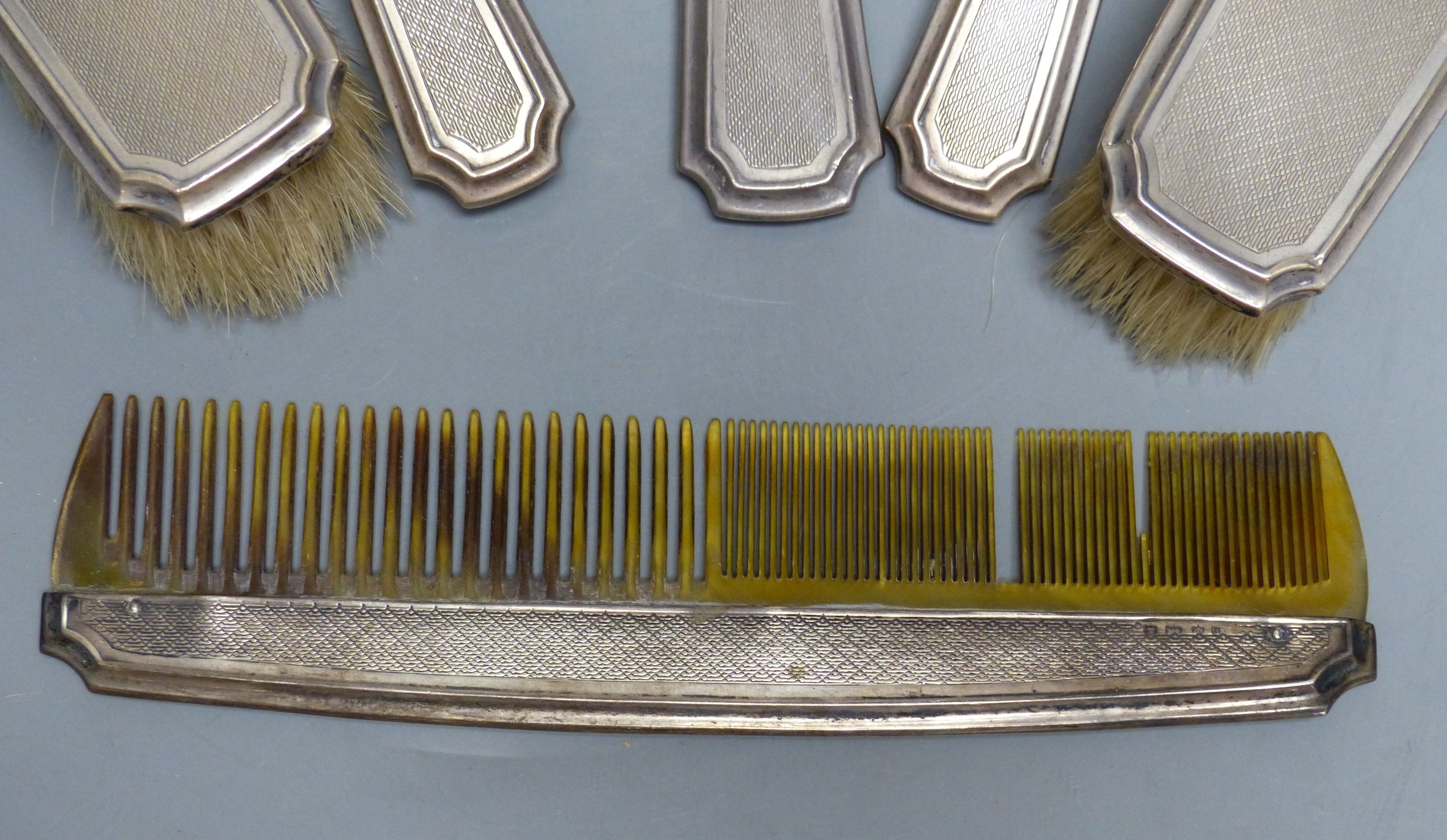 A six-piece engine-turned silver-mounted dressing table set, comprising two pairs of brushes, a comb and a hand mirror, Birmingham 1929